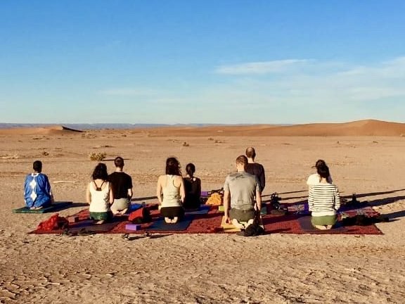 Gruppenmeditation in der Wüste bei Sonnenuntergang