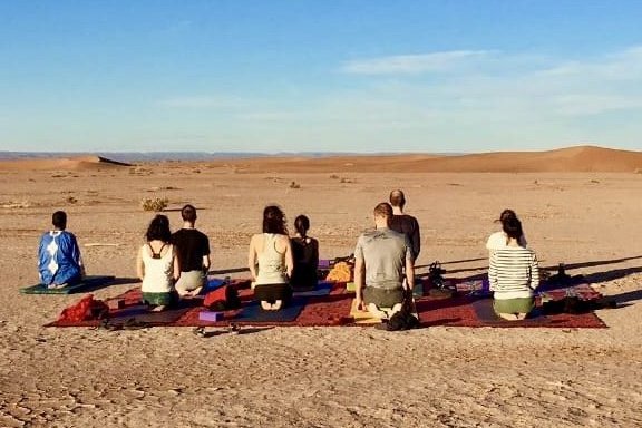 Gruppenmeditation in der Wüste bei Sonnenuntergang